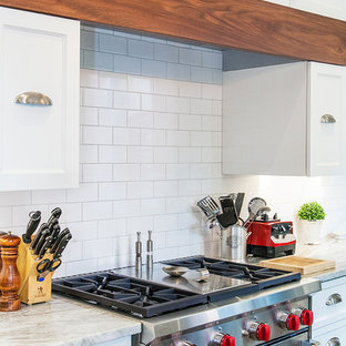 Exemple d'une très grande arrière-cuisine rétro en L avec un évier encastré, un placard à porte affleurante, des portes de placard blanches, un plan de travail en granite, une crédence blanche, une crédence en carrelage métro, un électroménager en acier inoxydable, un sol en carrelage de céramique et un îlot central.