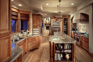 Inspiration for a large traditional u-shaped separate kitchen in Denver with a double-bowl sink, raised-panel cabinets, medium wood cabinets, granite benchtops, beige splashback, stone tile splashback, stainless steel appliances, light hardwood floors and with island.
