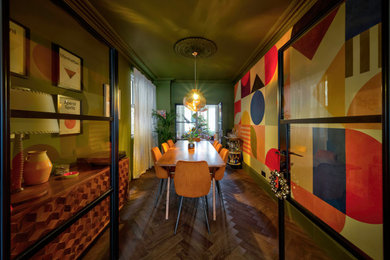 This is an example of a bohemian dining room in London with multi-coloured walls, dark hardwood flooring and brown floors.
