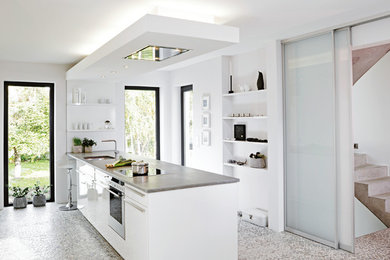 Geschlossene, Mittelgroße Moderne Küche mit Unterbauwaschbecken, flächenbündigen Schrankfronten, weißen Schränken, Betonarbeitsplatte, Küchengeräten aus Edelstahl und Halbinsel in Berlin