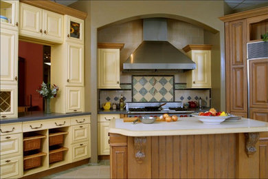 This is an example of a mid-sized mediterranean u-shaped eat-in kitchen in Los Angeles with raised-panel cabinets, yellow cabinets, quartz benchtops, multi-coloured splashback, porcelain splashback, stainless steel appliances and with island.