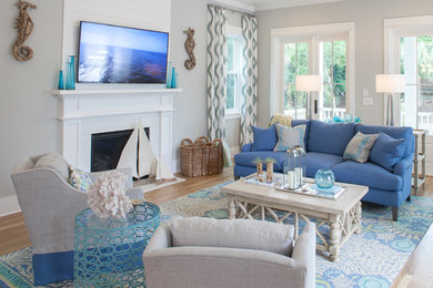 Design ideas for a beach style open concept family room in Raleigh with grey walls, light hardwood floors, a standard fireplace and a wall-mounted tv.