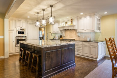 Design ideas for a large country eat-in kitchen in Kansas City with a farmhouse sink, beaded inset cabinets, granite benchtops, beige splashback, stone tile splashback, stainless steel appliances, dark hardwood floors and with island.
