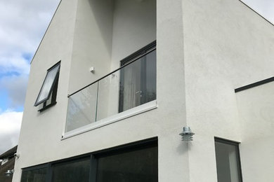 This is an example of a large and white contemporary render house exterior in Other with three floors and a pitched roof.
