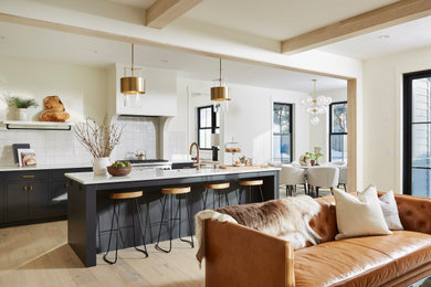 Large trendy l-shaped light wood floor and wood ceiling eat-in kitchen photo in Minneapolis with recessed-panel cabinets, black cabinets, quartzite countertops, white backsplash, ceramic backsplash, an island, white countertops, an undermount sink and paneled appliances