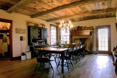 Photo of a large country dining room in Philadelphia with beige walls, light hardwood floors, a standard fireplace and a brick fireplace surround.