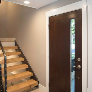 Cette image montre un hall d'entrée bohème de taille moyenne avec un mur beige, un sol en carrelage de porcelaine, une porte pivot et une porte en bois foncé.