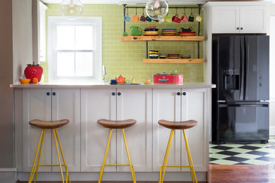 Inspiration for a mid-sized country u-shaped ceramic tile eat-in kitchen remodel in Philadelphia with a farmhouse sink, shaker cabinets, white cabinets, quartz countertops, green backsplash, subway tile backsplash, black appliances and a peninsula