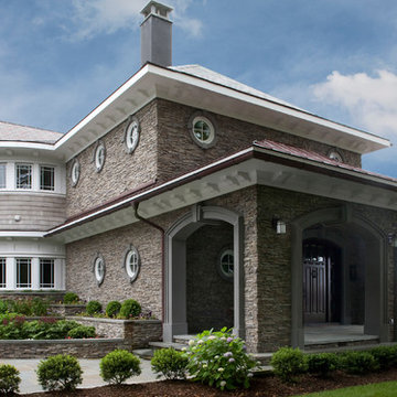 Nautical driveway and front entrance with circular windows and stacked stone ext