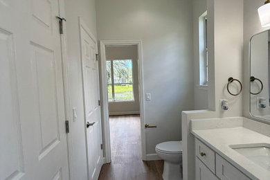 Inspiration for a mid-sized contemporary kids' white tile and cement tile laminate floor, beige floor and double-sink drop-in bathtub remodel in Other with shaker cabinets, white cabinets, a two-piece toilet, beige walls, an undermount sink, quartz countertops, white countertops, a niche and a built-in vanity