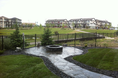 This is an example of a mid-sized traditional full sun backyard stone landscaping in Edmonton with a fire pit for summer.