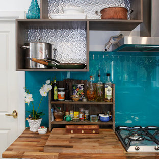 Idéer för att renovera ett mellanstort maritimt kök, med släta luckor, skåp i mörkt trä, träbänkskiva, blått stänkskydd, glaspanel som stänkskydd, rostfria vitvaror och ljust trägolv