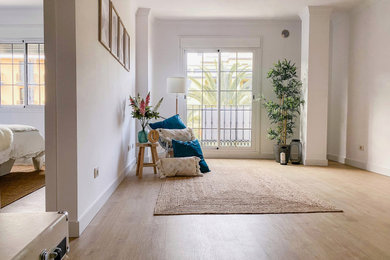 Imagen de salón abierto grande con paredes blancas, suelo de madera en tonos medios, pared multimedia y suelo beige