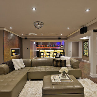 This is an example of a large contemporary look-out basement in Toronto with grey walls, laminate floors, a standard fireplace and a metal fireplace surround.