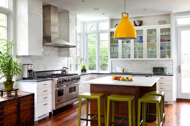 Example of a mid-sized trendy u-shaped medium tone wood floor open concept kitchen design in New York with an island, louvered cabinets, white cabinets, granite countertops, yellow backsplash, stone tile backsplash, stainless steel appliances and an undermount sink