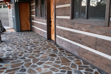 Mountain style stone wood railing porch idea in Other with a roof extension