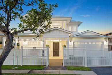 Photo of a large beach style two-storey white house exterior in Brisbane with concrete fiberboard siding, a gable roof and a metal roof.