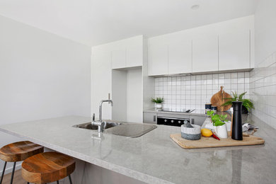 Design ideas for a small contemporary u-shaped open plan kitchen in Other with a drop-in sink, grey cabinets, laminate benchtops, white splashback, ceramic splashback, black appliances, vinyl floors, no island, brown floor and grey benchtop.