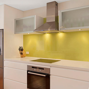 Photo of a medium sized contemporary u-shaped kitchen/diner in Sydney with a submerged sink, flat-panel cabinets, white cabinets, granite worktops, green splashback, glass sheet splashback, stainless steel appliances, medium hardwood flooring and a breakfast bar.