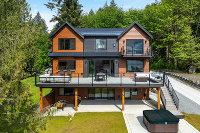 Mid-sized trendy multicolored three-story concrete fiberboard and clapboard exterior home photo in Vancouver with a metal roof and a black roof