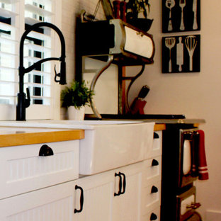 Idee per una cucina di medie dimensioni con lavello stile country, ante a filo, ante gialle, top in legno, paraspruzzi giallo, paraspruzzi in perlinato, elettrodomestici in acciaio inossidabile, pavimento in legno massello medio, isola, pavimento marrone, top arancione e travi a vista