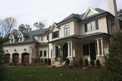 This is an example of a large traditional two-storey stucco white house exterior in New York with a gable roof and a shingle roof.