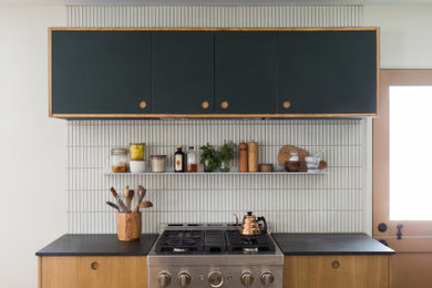 Kitchen - small 1950s l-shaped terrazzo floor and multicolored floor kitchen idea in Los Angeles with an undermount sink, flat-panel cabinets, green cabinets, granite countertops, white backsplash, ceramic backsplash, an island and black countertops