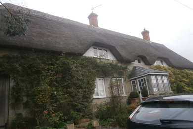 This is an example of an expansive and beige farmhouse two floor detached house in Hampshire with a hip roof, a mixed material roof and a brown roof.