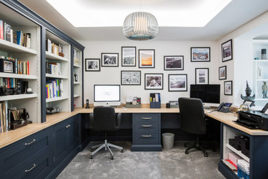 This is an example of a mid-sized contemporary study room in Kent with white walls, carpet, no fireplace, a built-in desk and grey floor.