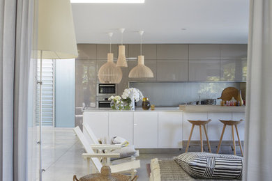 Design ideas for a mid-sized contemporary galley open plan kitchen in Sydney with a double-bowl sink, flat-panel cabinets, white cabinets, solid surface benchtops, glass sheet splashback, stainless steel appliances, concrete floors, with island and grey floor.