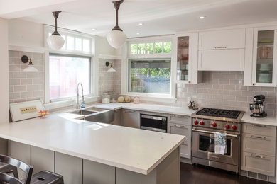 Photo of a mid-sized eclectic u-shaped eat-in kitchen in Other with a farmhouse sink, shaker cabinets, grey cabinets, quartz benchtops, grey splashback, subway tile splashback, dark hardwood floors, a peninsula and stainless steel appliances.