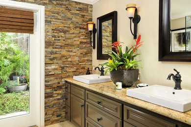 Inspiration for a large master multicolored tile and stone tile limestone floor, beige floor and double-sink corner shower remodel in San Francisco with raised-panel cabinets, brown cabinets, a two-piece toilet, beige walls, a vessel sink, granite countertops, a hinged shower door, multicolored countertops and a built-in vanity