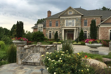 Photo of a huge traditional full sun front yard stone landscaping in DC Metro.