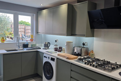 Inspiration for a medium sized u-shaped enclosed kitchen in West Midlands with an integrated sink, flat-panel cabinets, green cabinets, quartz worktops, white splashback, stone slab splashback, black appliances, porcelain flooring, no island, grey floors, white worktops and a coffered ceiling.