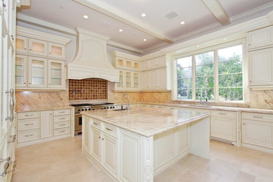 This is an example of a large traditional u-shaped separate kitchen in Miami with an undermount sink, raised-panel cabinets, white cabinets, marble benchtops, brown splashback, marble splashback, panelled appliances, travertine floors, with island and beige floor.