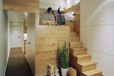 Photo of a contemporary loft-style bedroom in New York with white walls and dark hardwood floors.