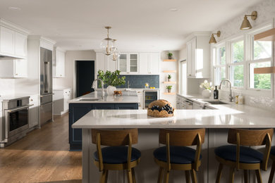 Eat-in kitchen - transitional l-shaped medium tone wood floor eat-in kitchen idea in Milwaukee with recessed-panel cabinets, white cabinets, quartzite countertops, blue backsplash, stainless steel appliances, an island and white countertops