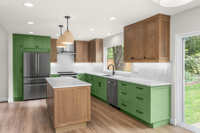 Inspiration for a mid-sized transitional l-shaped medium tone wood floor and beige floor kitchen remodel in Portland with a drop-in sink, shaker cabinets, green cabinets, quartzite countertops, white backsplash, mosaic tile backsplash, stainless steel appliances, an island and white countertops