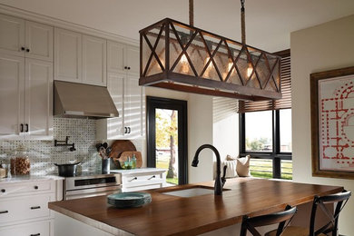 Example of a farmhouse dark wood floor and brown floor kitchen design in Other with an undermount sink, shaker cabinets, white cabinets, wood countertops, white backsplash, mosaic tile backsplash, stainless steel appliances and an island