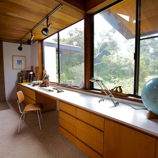 Photo of a mid-sized midcentury craft room in San Diego with white walls, a wood stove and a built-in desk.