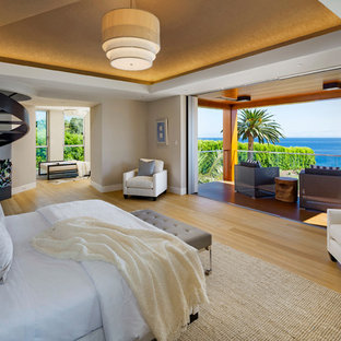 Inredning av ett modernt stort huvudsovrum, med vita väggar, ljust trägolv, en standard öppen spis och en spiselkrans i betong