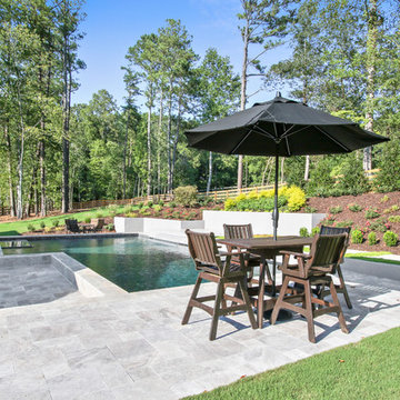 Contemporary style pool with silver travertine deck and custom water feature