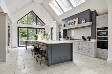 Large transitional galley open plan kitchen in Manchester with a drop-in sink, shaker cabinets, grey cabinets, quartzite benchtops, white splashback, engineered quartz splashback, stainless steel appliances, with island and white benchtop.