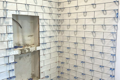 Inspiration for a mid-sized cottage master white tile and ceramic tile porcelain tile, green floor and single-sink bathroom remodel in Other with furniture-like cabinets, brown cabinets, a one-piece toilet, white walls, an undermount sink, quartz countertops, white countertops, a niche and a freestanding vanity