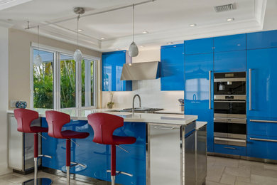 Inspiration for a mid-sized u-shaped travertine floor, beige floor and coffered ceiling kitchen pantry remodel in Miami with a single-bowl sink, flat-panel cabinets, blue cabinets, quartzite countertops, white backsplash, stone slab backsplash, stainless steel appliances, an island and white countertops
