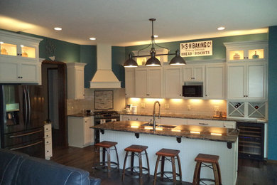 Kitchen - traditional dark wood floor and brown floor kitchen idea in Cleveland with an undermount sink, glass-front cabinets, white cabinets, granite countertops, white backsplash, ceramic backsplash, stainless steel appliances and an island
