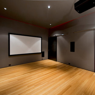 Idées déco pour une salle de cinéma contemporaine de taille moyenne et fermée avec un mur gris, un sol en bambou et un écran de projection.