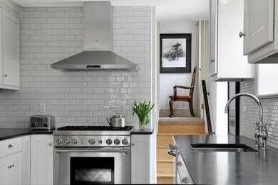 Example of a mid-sized classic l-shaped linoleum floor kitchen pantry design in Philadelphia with an undermount sink, shaker cabinets, white cabinets, soapstone countertops, white backsplash, ceramic backsplash, stainless steel appliances and a peninsula