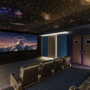 Photo of a large contemporary enclosed home cinema in New Orleans with blue walls, carpet, a projector screen and blue floors.