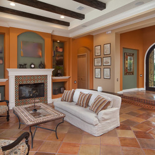 Modelo de salón para visitas abierto, mediterráneo, grande, sin televisor, con parades naranjas, suelo de baldosas de terracota, chimenea tradicional y marco de chimenea de baldosas y/o azulejos